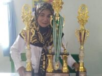 Kepala MI Al-Jannah Cihampelas KBB, Rini Resmiati, S.Pd.I., M.M bangga memperlihatkan sejumlah piala prestasi siswanya. (Dadan Saepudin/Mediaseruni)